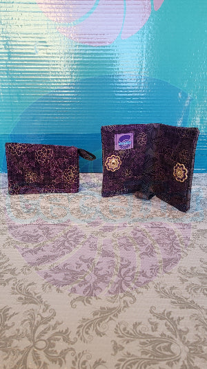 A purple wallet with gold lotus flower detail, displayed in an open and closed position, showcasing its compact design and push button closure.