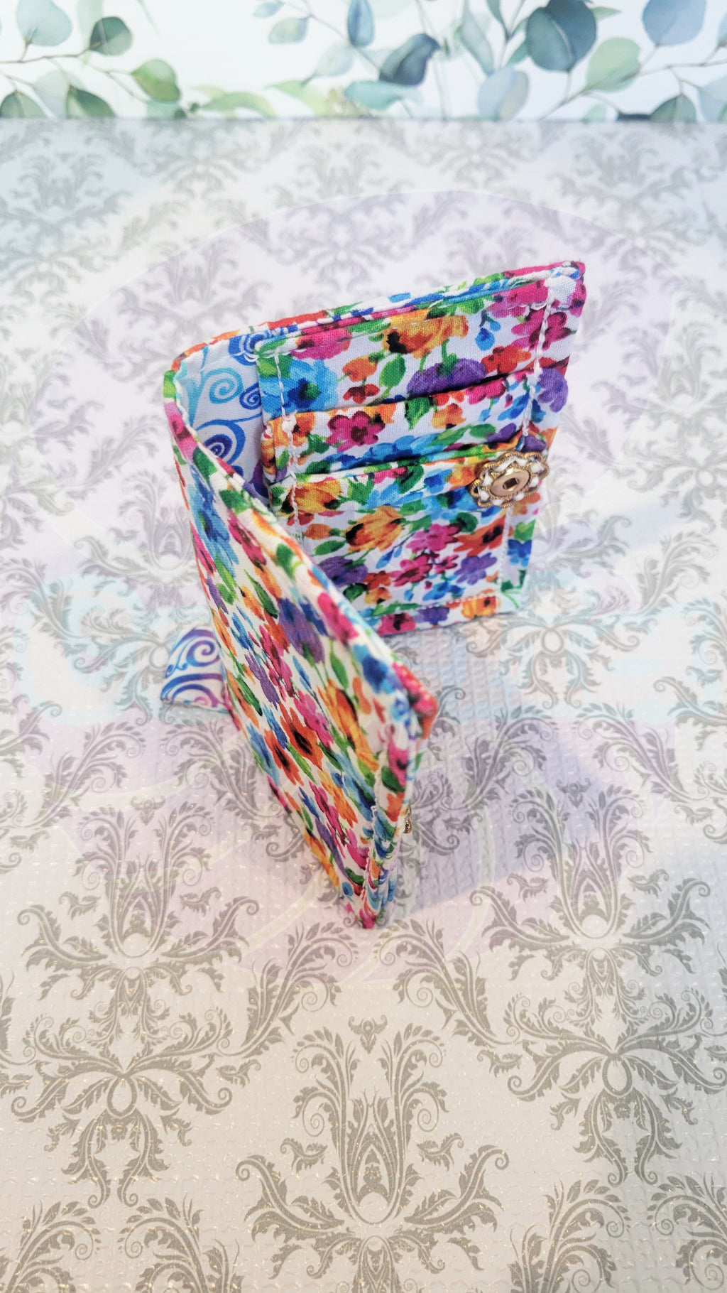 Colorful floral wallet on a patterned surface