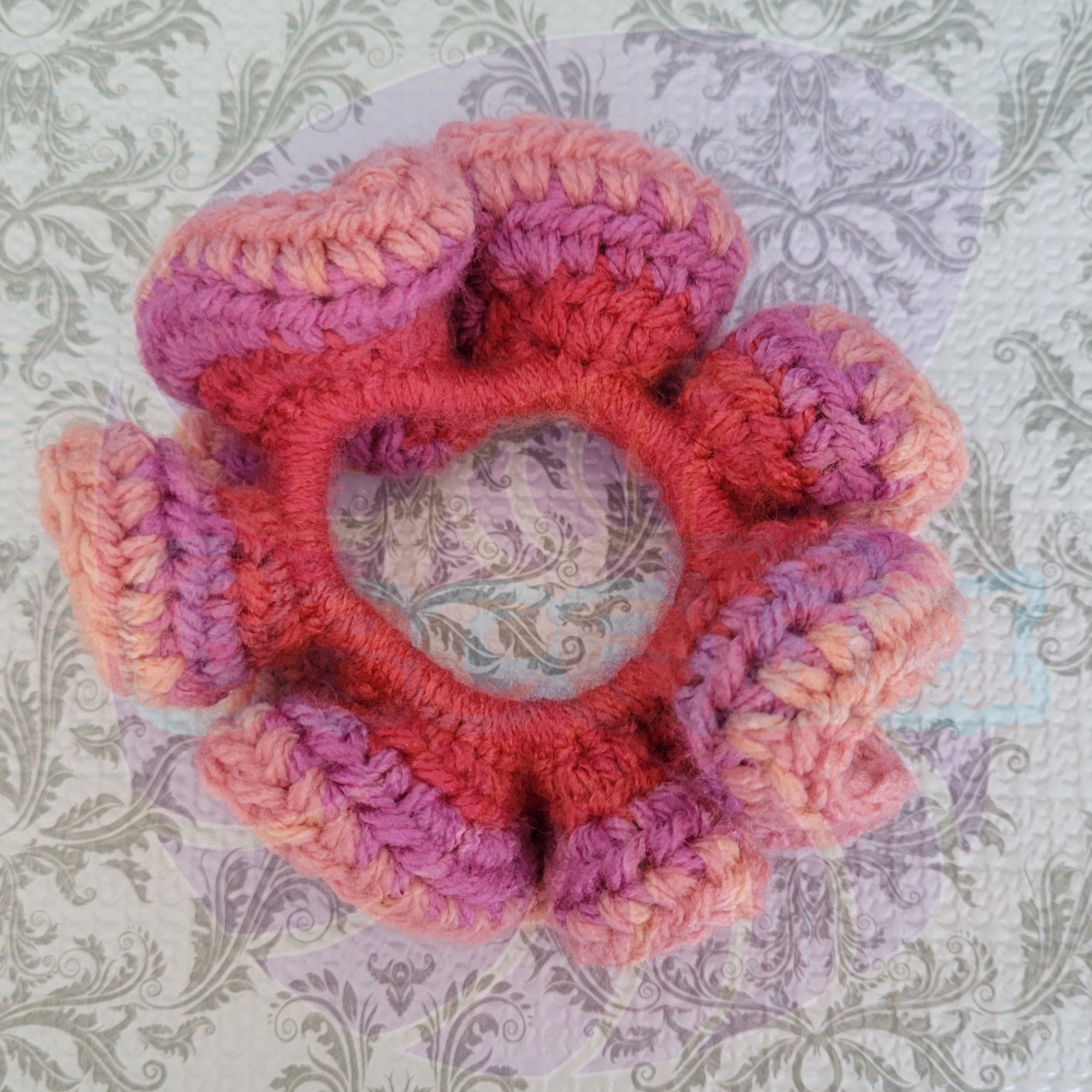 Crocheted scrunchie with pink and orange colors on a patterned background