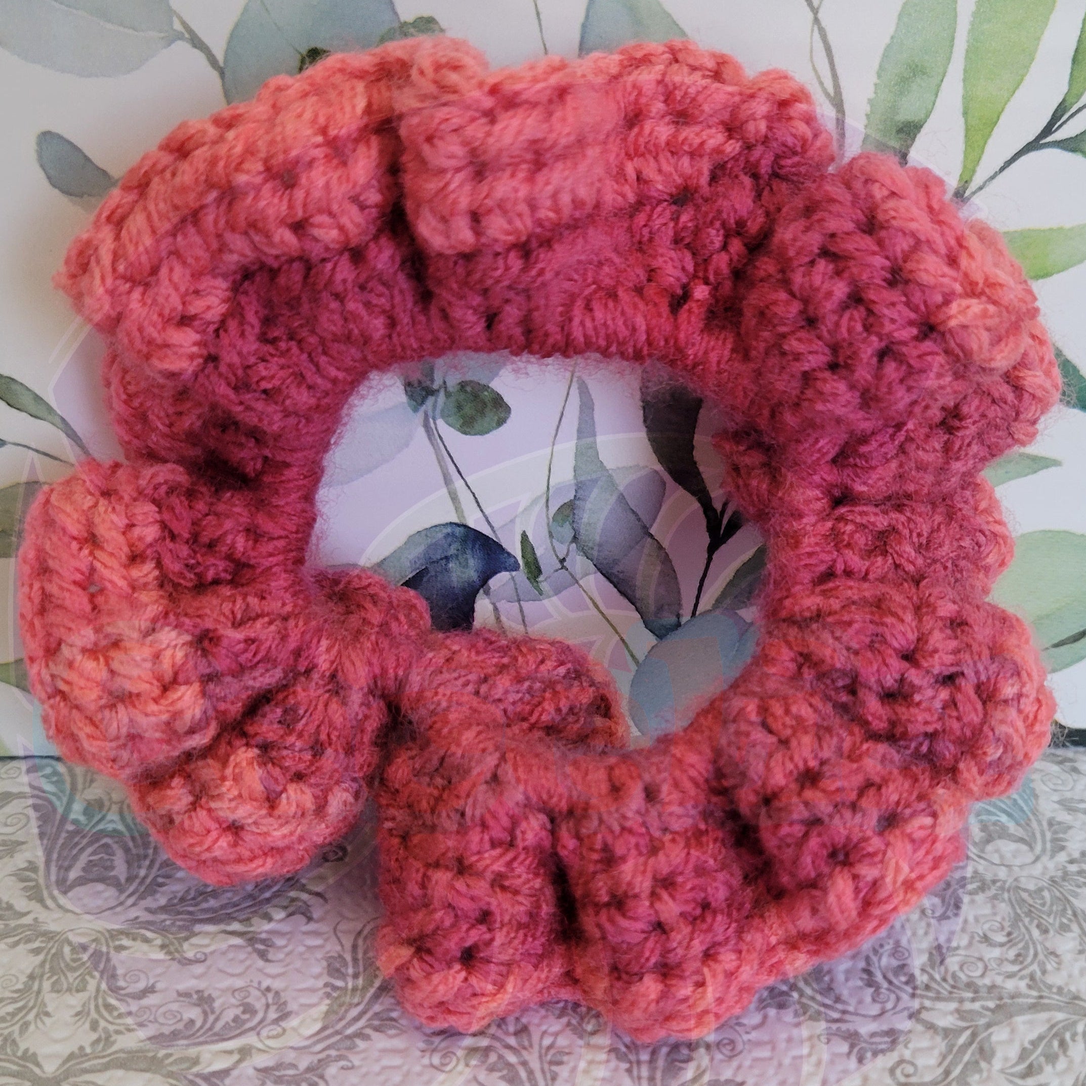 Pink crochet scrunchie on a floral-patterned background