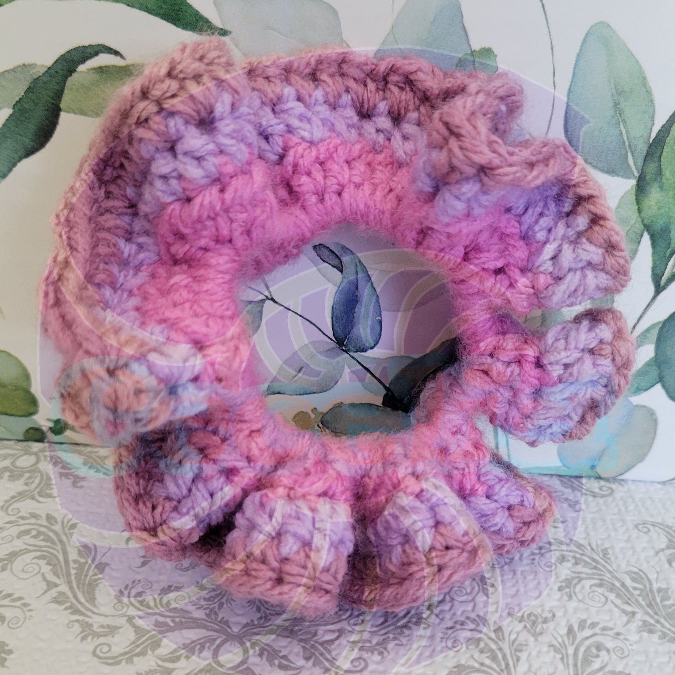 Pink and purple crocheted scrunchie on a floral background